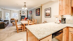 A spacious kitchen with wooden cabinets, a granite countertop, and a dining area with a wooden table and chairs. - Village Chateaux Falcon SuperChair Condo: Great Location (Breckenridge)