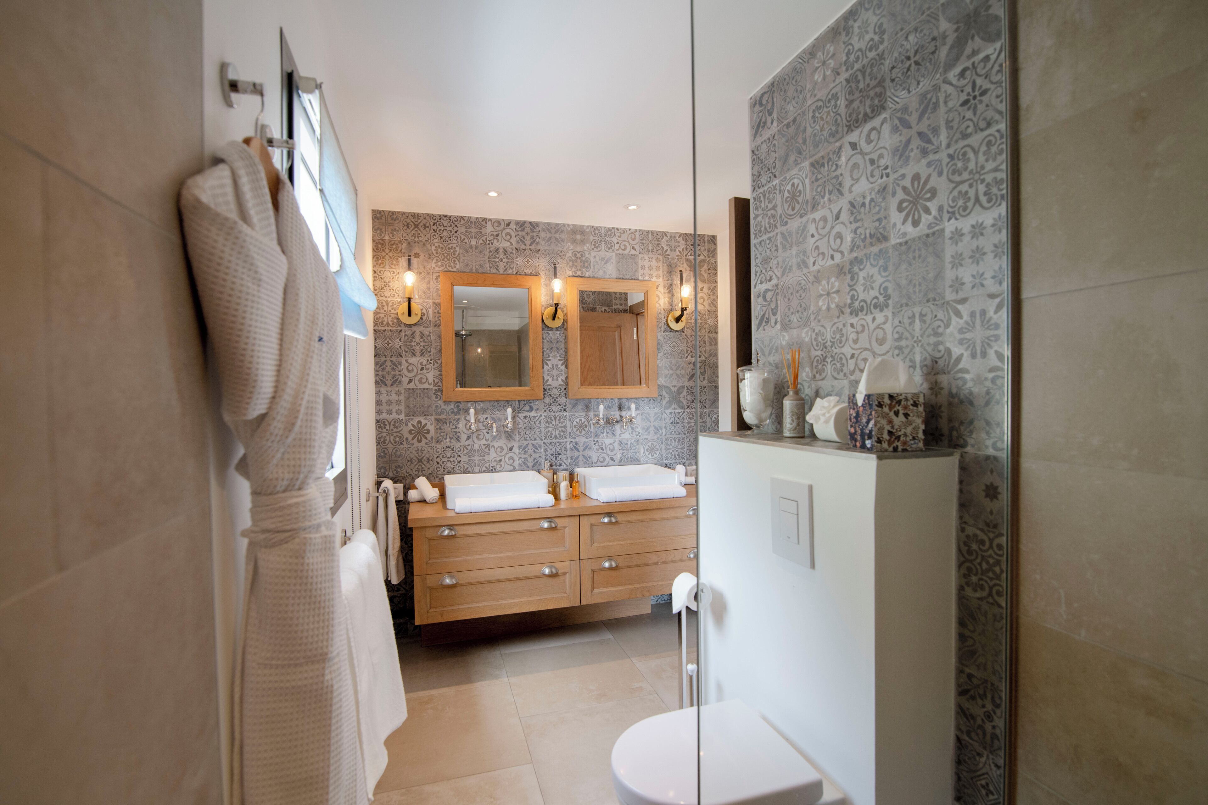 A modern bathroom with a double sink vanity, a large mirror, and patterned tiles.