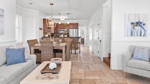 A spacious living area with a dining table, sofas, and a kitchen in the background.
