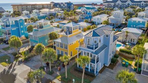 A coastal residential area with colorful houses, a clear view of the ocean, and a well-maintained lawn.