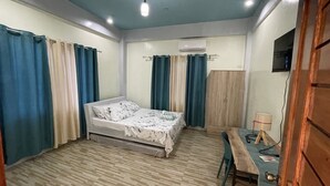 A bedroom with a bed, curtains, a desk, and an air conditioning unit.