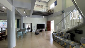 A spacious living area with a large TV, a staircase, and a dining area.