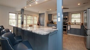 A spacious kitchen with a central island, bar stools, and a sign indicating a 'CRAB HOUSE'.