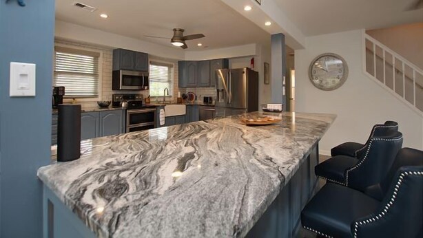 A modern kitchen with a marble island, stainless steel appliances, and a sign reading "CRAB HOUSE".