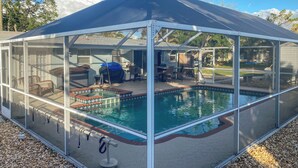 Una piscina scoperta coperta, con struttura in vetro, circondata da mobili da patio e una piccola zona prendisole.