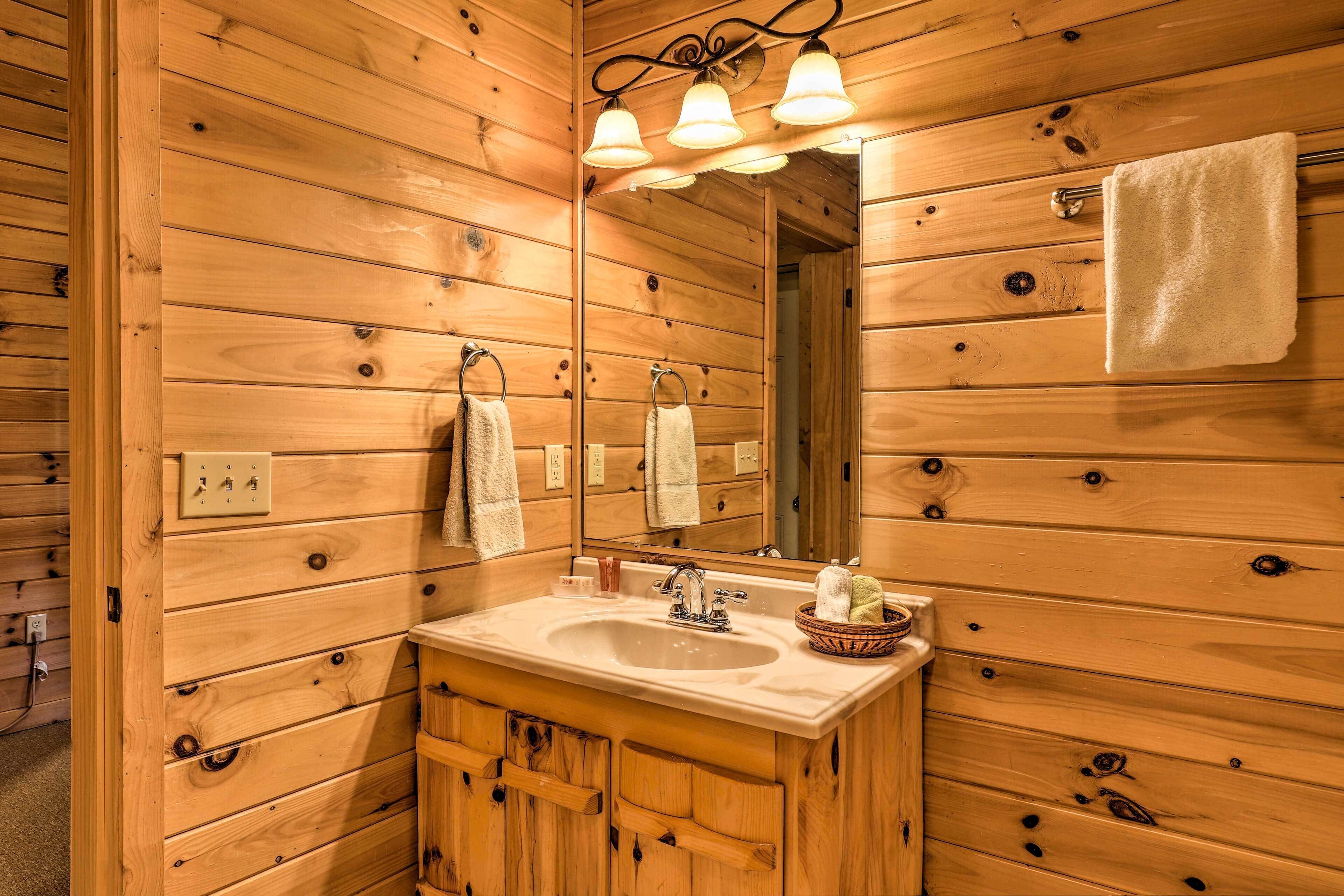 Un baño estilo cabaña de madera con tocador de madera, un lavabo, un espejo y una toalla colgada en la pared.