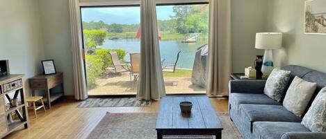 A living room with a sofa, coffee table, and a view of a lake through large windows.