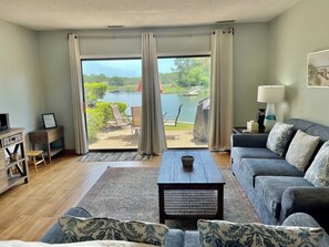 A living room with a sofa, coffee table, and a view of a lake through large windows.