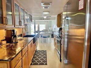 Une cuisine moderne avec des meubles en bois, des appareils en acier inoxydable et un coin repas comprenant une table et des chaises.