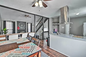 Enjoy meals in this stylish dining area with a table for four, a ceiling fan, and a stainless steel range hood.