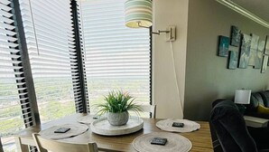 Un coin repas avec une table en bois, des chaises blanches et une plante en pot.