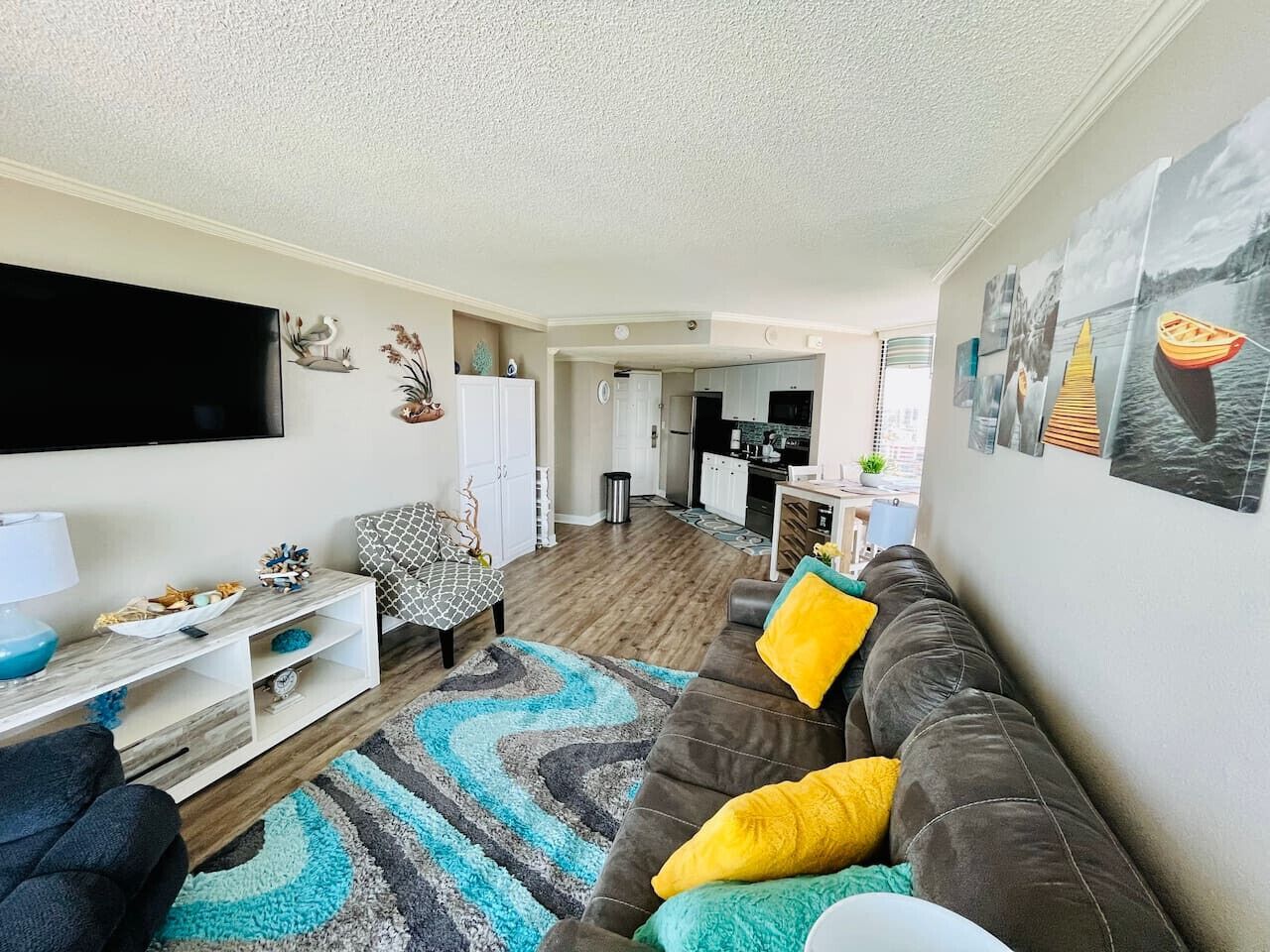 A modern living room with a sofa, TV, and a kitchen in the background.