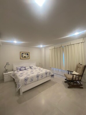 Cozy retreat with a neatly made bed, bedside table, and a comfortable rocking chair.