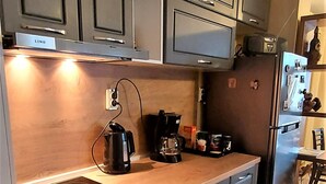 Moderni keittiö, jossa on harmaat kaapit, sisäänrakennettu uuni, liesi ja jääkaappi.