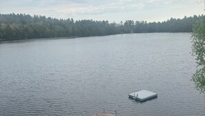 A lake with a dock and a boat, surrounded by trees. - Heart Lodge,slg fam sleeps 11, Lakefront great swimming / fishing kayaks, padbd. (Orland)