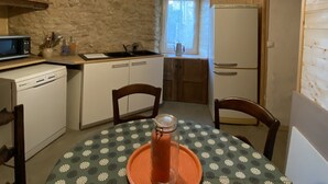 Une cuisine compacte aux murs en bois, dotée d’un évier encastré, d’un réfrigérateur et d’une table à manger recouverte d’une nappe à motifs.