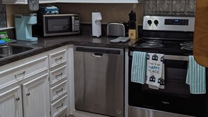 A kitchen with white cabinets, a microwave, a coffee maker, a dishwasher, and a stove. - Robyn's Nest (North Charleston)