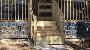 A two-story house with a wooden deck, a green balcony, and a staircase leading to the upper floor. - Robyn's Nest (North Charleston)