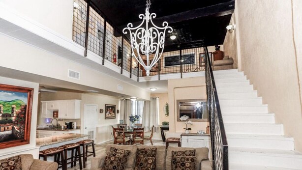 A spacious living area with a high ceiling, a staircase, and a dining area.