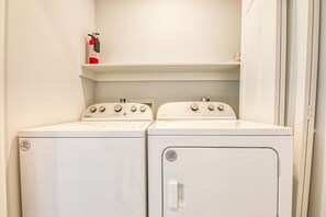A laundry room with two front-loading washing machines and a dryer.