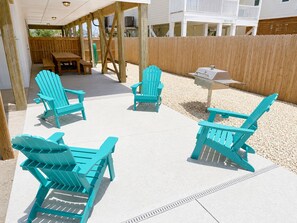 An outdoor patio with turquoise Adirondack chairs, a grill, and a wooden deck. - For Fox Sake–Family-Friendly Gulf Escape-Sleeps 22 (Gulf Shores)