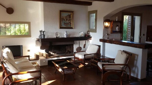 A cozy living room with a fireplace, comfortable seating, and a television. - Villa with land, close to the sea, beach, tennis court... (corbara)