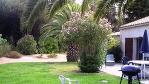 A garden with a barbecue grill, a white plastic chair, and a table with chairs. - Villa with land, close to the sea, beach, tennis court... (corbara)