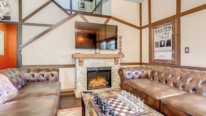 A living room with a fireplace, leather sofas, a chessboard, and a staircase. - Harry Potter House at Regal Palms | Sage Vacations (Davenport)