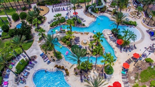 A resort with multiple swimming pools, palm trees, and sun loungers. - Harry Potter House at Regal Palms | Sage Vacations (Davenport)