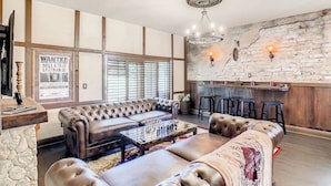 A spacious living room with a large sofa set, a coffee table with chess pieces, a stone accent wall, and a bar area with stools. - Harry Potter House at Regal Palms | Sage Vacations (Davenport)