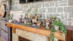 A stone fireplace with a wooden mantel decorated with plants, candles, and books. - Harry Potter House at Regal Palms | Sage Vacations (Davenport)