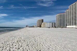 A beach with a row of high-rise buildings in the background. - Gulf Shores Beach House | Mini Golf & Giant Chess | 1 Block to Beach | Pets OK (Gulf Shores)