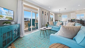 Un salon spacieux avec un canapé bleu, un meuble turquoise et une grande fenêtre donnant sur la ville.