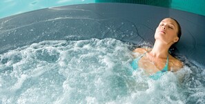 Une personne dans un bain à remous, avec des jets d’eau visibles.