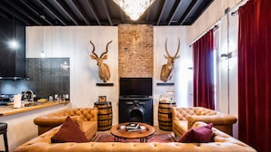 A modern living room with a fireplace, leather sofas, and antlered deer mounted on the wall. - The Rickhouse in NuLu~2 King Bed/2 Full Bath (Louisville)