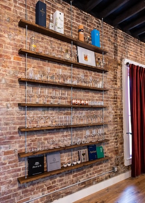 A brick wall with shelves displaying various glassware and bottles.