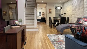 Ein modernes Wohnzimmer mit Treppe, Holzboden und Essbereich.