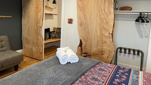 Ein gemütliches Zimmer mit einem Bett, einer Bank und einem Schrank mit Holzoptik.