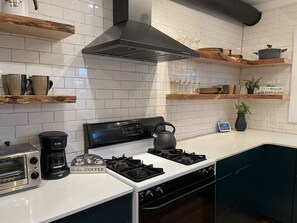 A modern kitchen with white tiled walls, a gas stove, a coffee maker, and a toaster. - Row-home 3min drive to Central Market,Office,Patio w/ Fire Pit, Artistic Accents (Lancaster)