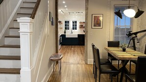 Eine Treppe führt zu einer Küche mit Holzboden, einem Essbereich mit Tisch und Stühlen sowie einem auf einem Stativ stehenden Teleskop.