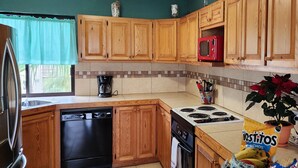 A kitchen with wooden cabinets, a microwave, a dishwasher, a stove, and a countertop with a coffee maker.