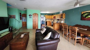 A living room with a sofa, coffee table, and a dining area with chairs and a table.