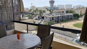 A balcony with a table and chairs, overlooking a street with cars and buildings.