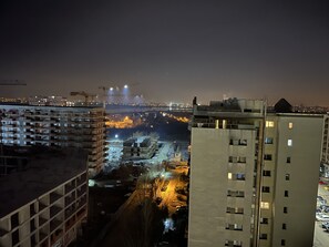 Ein Nachtblick auf eine Stadtlandschaft mit Hochhäusern, Baustellen und einem Fluss.