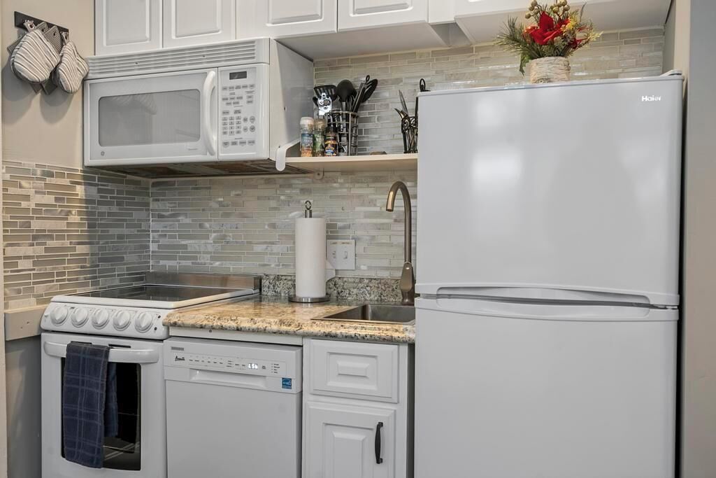 Una cocina con microondas, estufa, lavavajillas y refrigerador.