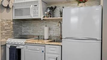 Una cocina con microondas, estufa, lavavajillas y refrigerador.