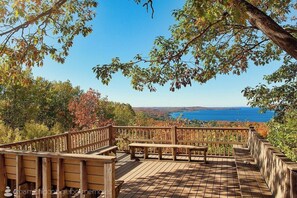 Une terrasse en bois, dotée de bancs, qui offre une vue panoramique sur un lac et une forêt.