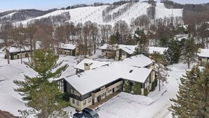 Zona residencial nevada con casas y una pista de esquí al fondo.