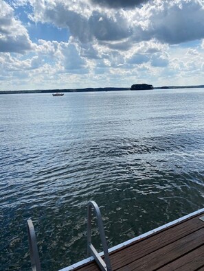 A view from a boat on a calm body of water with a distant island and a small boat in the distance. - DREHER DREAMS CABIN-LAKEFRONT- + FISHING, KAYAKS,PADDLEBOARDS, 7 BEDS SLEEPS 9!  (Prosperity)