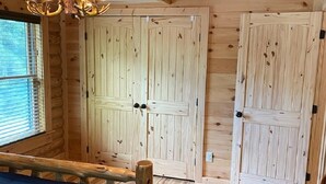 Habitación de cabaña de madera con una cama, una silla y dos puertas.